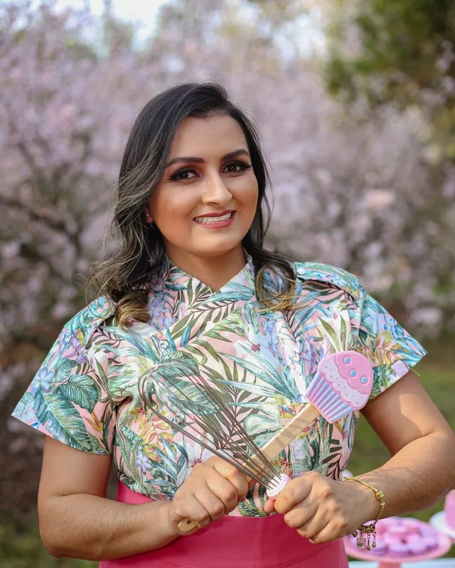 Lika Silva, confeiteira da Lika Cakes, segurando um batedor entre cerejeiras